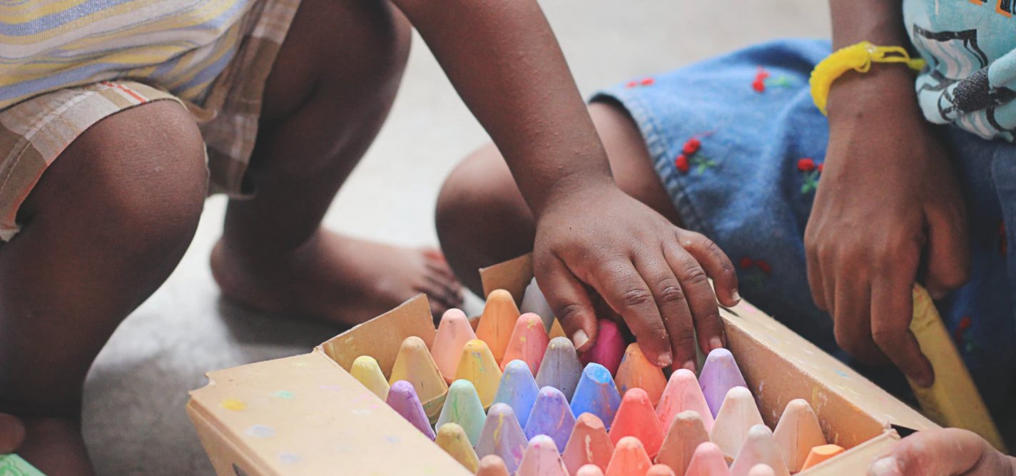 Child's hand reaching for colored chalk